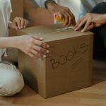 A couple unpacking books in their new home, focusing on teamwork and domestic life.